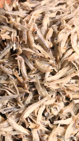 Closeup of tiny dried fish similar to anchovies used as snack or ingredient in soups popular in Asia and Europe showing texture size and food presentation