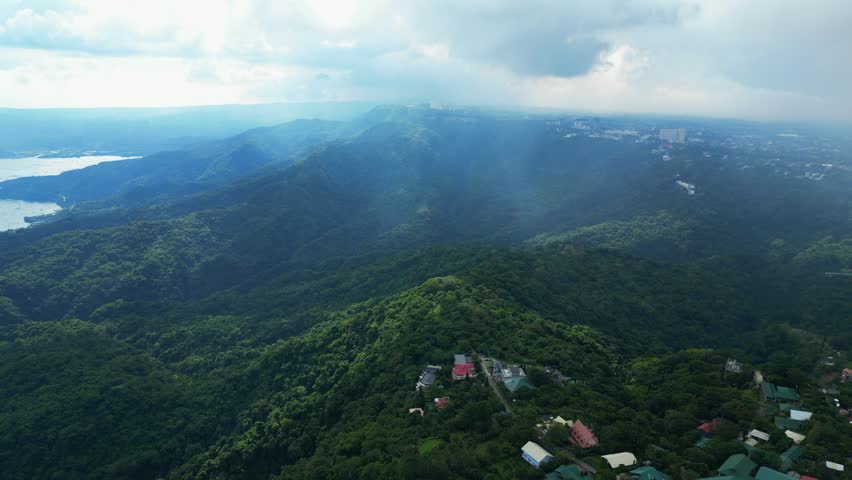 A pull-back wide aerial of mist-covered forested hills and lush greenery in Talisay, Batangas, Philippines