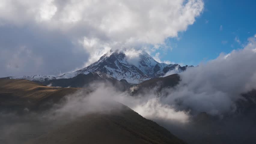 Majestic Snow-Capped Mountain Peaks Surrounded by Dramatic Clouds in a Serene Landscape