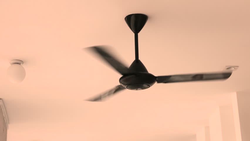 Black ceiling fan slowly spinning in residential room providing indoor cooling