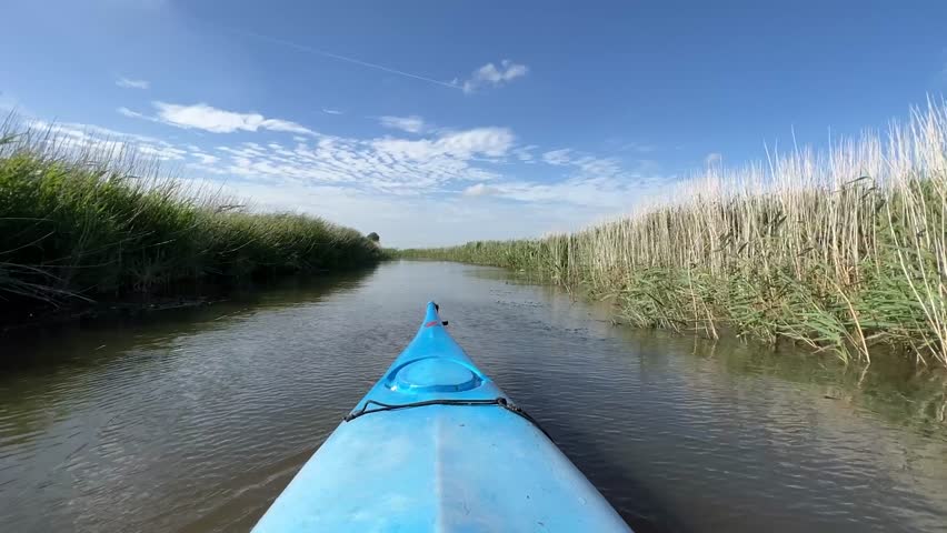 Canoeing through a canal at the farmland of Friesland the Netherlands