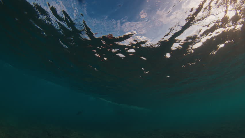 Underwater view of the surfer riding the ocean wave