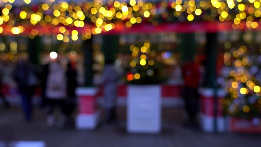 Blurred christmas market with Christmas decorations. People shop gifts and souvenirs on New Years fair of evening city in defocus.