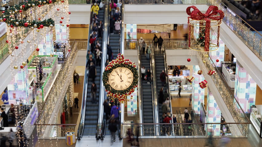 High-angle view of a bustling shopping mall decorated for Christmas with festive lights and ornaments. Time-lapse.
