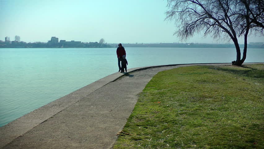 Mother and little boy having a walk in the park near lake