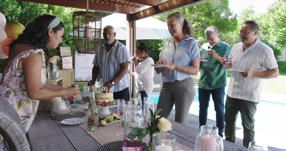 Woman host placing tiered cake, guests stepping forward reaching plates, sparkles overlaying event. Backyard, poolside, patio, balloons, gifts, candles, centerpiece