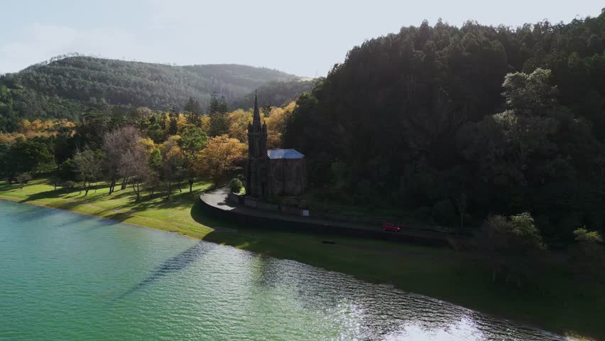 Breathtaking aerial view captured by a drone of the Nossa Senhora das Vitórias Chapel (Chapel of Our Lady of Victories) located on the edge of the scenic Furnas Lake in São Miguel, Azores, Portugal. 
