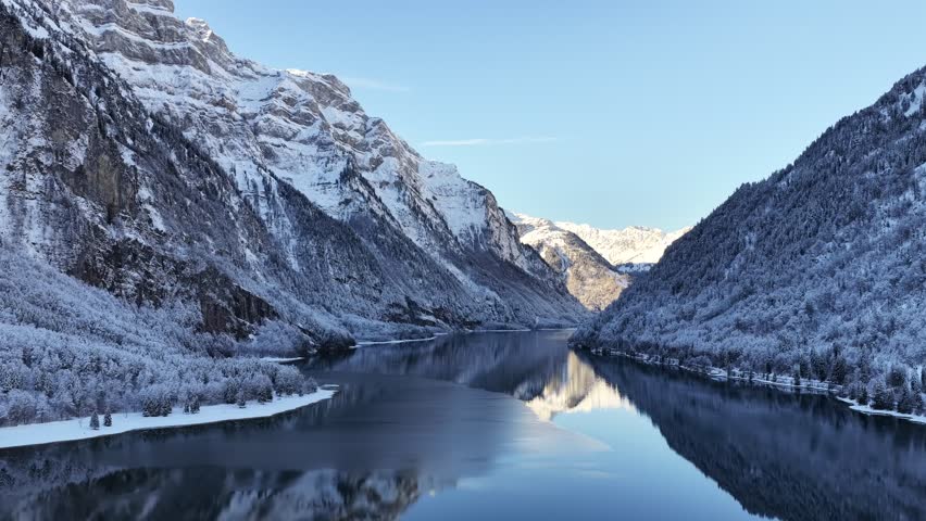 Snowy alpine mountains reflecting on Klöntalersee in winter Switzerland