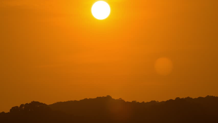 Scenic sunset time-lapse over natural landscape, revealing dawn colors and misty atmosphere.