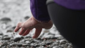 Hand wave pebble, woman dips into cold ocean water as foamy wave washes ashore on a rocky beach. - Powered by Shutterstock - Get 15% off with code: PIKWIZARD15