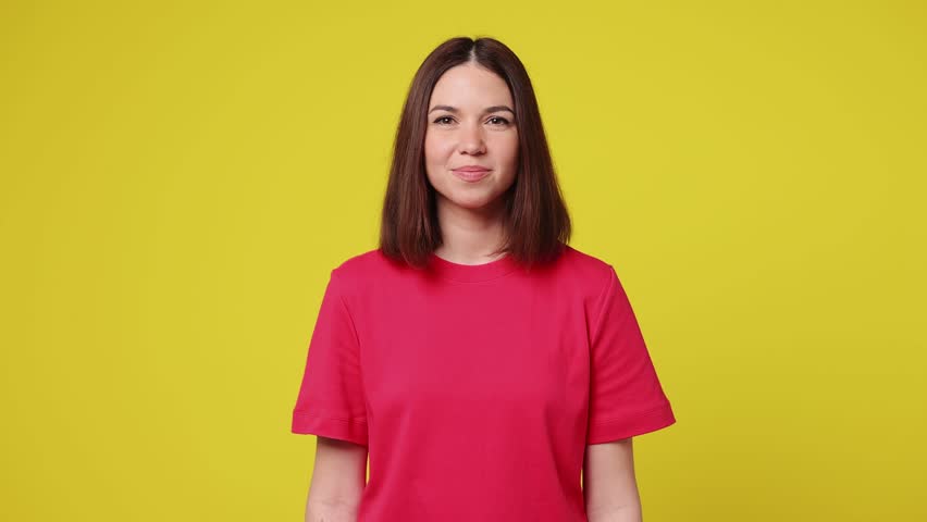 Excited jubilant overjoyed happy young woman wear pink t-shirt casual clothes doing winner gesture celebrate clenching fists say yes isolated on plain yellow color background studio Lifestyle concept