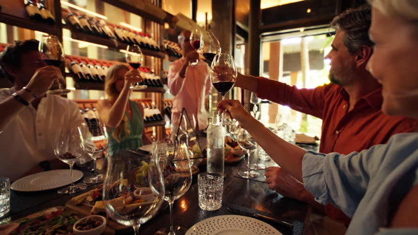 Group of friends raise their glasses in a joyful toast during a private wine tasting in a luxury cellar. Captures celebration, friendship, fine wine, gourmet dining, and an upscale social atmosphere.