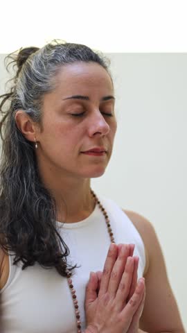 Mature woman with closed eyes meditating peacefully. Spiritual yoga instructor practicing mindfulness in a calm and tranquil state