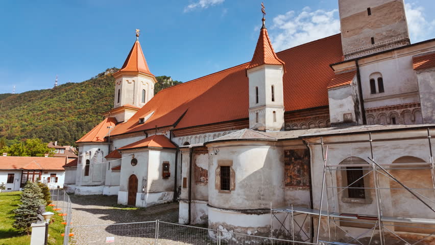 St Nicholas Church, Brasov, Transylvania, Romania, with a tall tower, painted porch and quiet square
