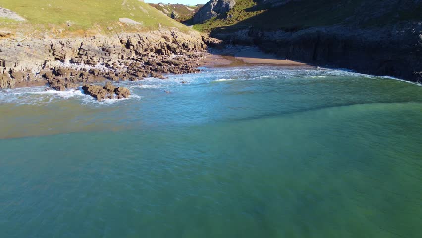 Fast Approach to Beach at High Tide with Small Patch of Sand as Waves Roll In. Beautiful Welsh Coastline with Rock Pools and Deep Valley. Travel Nature Drone Clip.