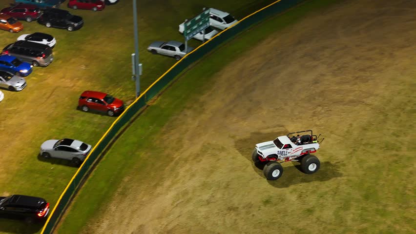 Monster truck drives through grass field at Summer Sam Jam carnival in Woodhaven, Michigan, USA