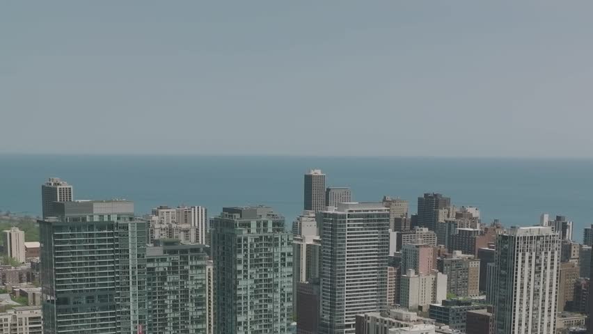 The skyline of Chicago showcases a mix of modern buildings and historic architecture, while Lake Michigan stretches to the horizon under a clear blue sky.