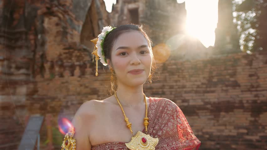 Portrait of Young thai woman wearing a beautiful traditional dress smiles at a temple in Ayutthaya, Thailand