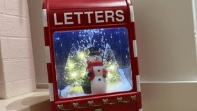 Christmas decoration with a snowman inside a red letters mailbox. Artificial snow and lights create a festive holiday scene indoors. - Powered by Shutterstock - Get 15% off with code: PIKWIZARD15