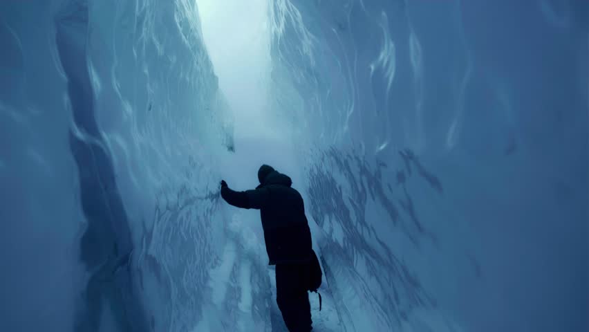 Blue ice cave in white glacier on Antarctic. Aerial shot close-up. Antarctica panoramic drone flight view. Snow among polar ice. Cave in iceberg around frozen water. Permafrost. Antarctic