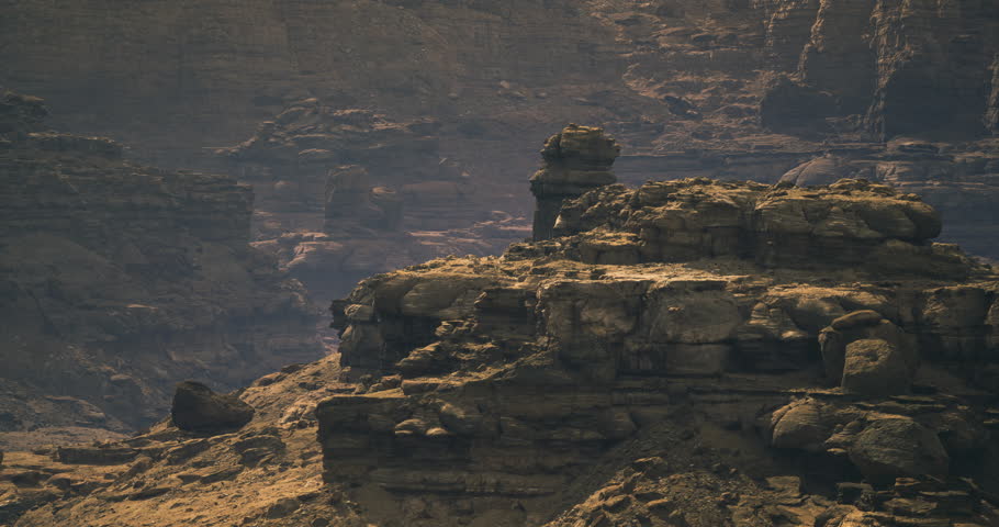 Unique rock formations are highlighted by soft light in a rugged terrain. Shadows and textures create a dramatic atmosphere in this natural setting.