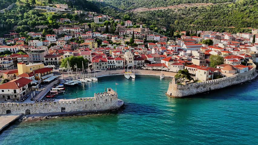Aerial drone footage capturing the Venetian Harbour of Nafpaktos, Greece, with its iconic circular port, stone walls, and entrance towers. 