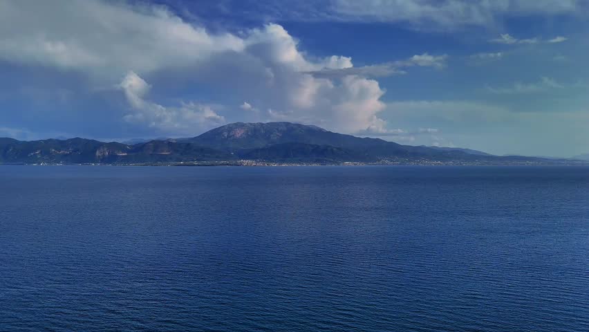 Aerial drone footage filmed from Nafpaktos, Greece, showing the coastline and open sea looking toward the Peloponnese. 