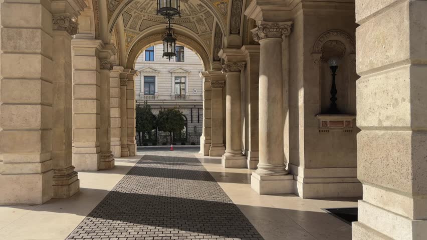 Part of ceiling with decorative vault and hanging lamps in main entrance portico of the Hungarian State Opera House of 19th century in Budapest at sunny day, bottom-up view while vertical panning
