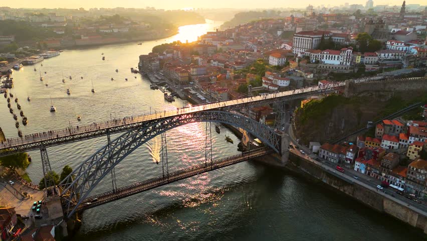 Cinematic Drone Sunset Over Porto, Portugal — Golden Light on the Douro River and Dom Luís I Bridge with Stunning Cityscape View. 