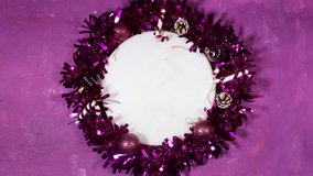 Festive purple Christmas wreath laid flat on a purple backdrop, featuring glossy ornaments, frosted pine cones, candy canes, and shimmering tinsel surrounding a central white space - Powered by Shutterstock - Get 15% off with code: PIKWIZARD15
