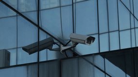 4K Security Cameras on Modern Glass Building Facade Surveillance, selective focus. - Powered by Shutterstock - Get 15% off with code: PIKWIZARD15