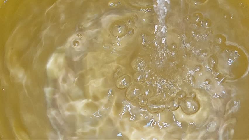 Golden liquid, abstract oil bubbles, cosmetic serum texture, flowing water background video 