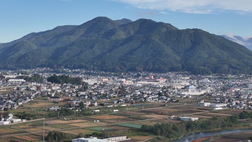 A mountain range is visible in the background of a city. The city is full of houses and buildings, and the mountains are in the distance