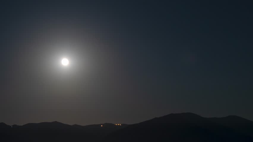 View of moon over mountain at night time lapse