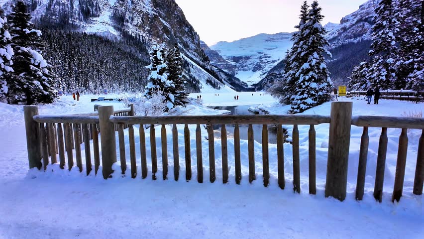 Frozen Lake Louise surrounded by snowy peaks and pine trees in Banff National Park. Calm winter atmosphere, soft light, untouched snow and a classic cozy Christmas-like scenery.
