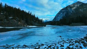 Frozen river and a small winter waterfall in Banff, Canada. Snowy rocks, icy shoreline and pine-covered cliffs create a calm North American winter landscape. - Powered by Shutterstock - Get 15% off with code: PIKWIZARD15