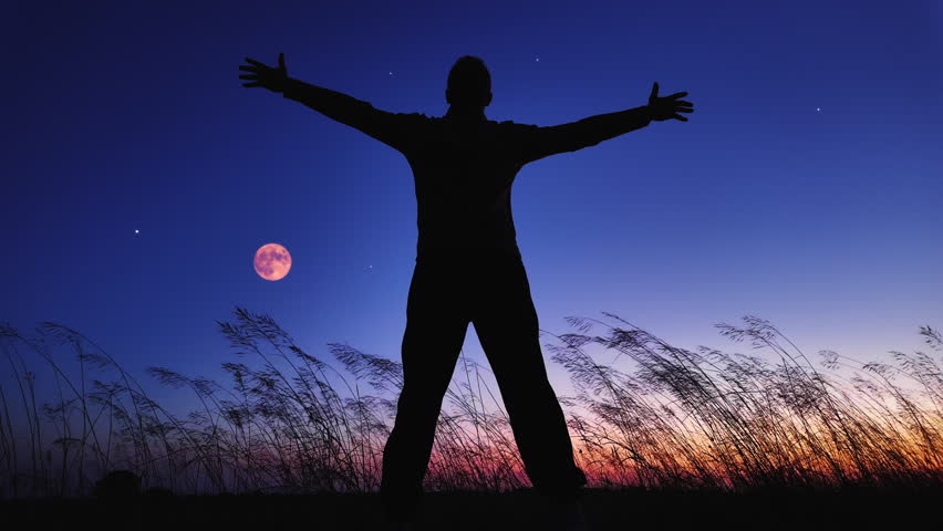 Silhouette of a man and countryside under the Moon, stars and planets in blue hour time.