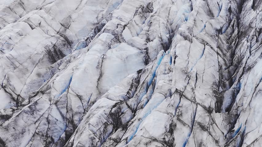 Aerial beautiful day view of Svínafellsjökull Glacier, Iceland. The breathtaking Svinafellsjokull Glacier cascades majestically into the still waters below, framed by rugged mountains with some mist.