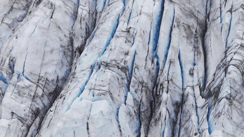 Aerial beautiful day view of Svínafellsjökull Glacier, Iceland. The breathtaking Svinafellsjokull Glacier cascades majestically into the still waters below, framed by rugged mountains with some mist.