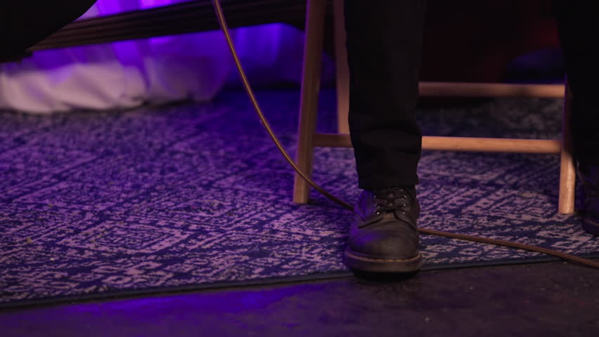 A Bass Player Taps His Foot While Playing The Instrument. Panning up Shot