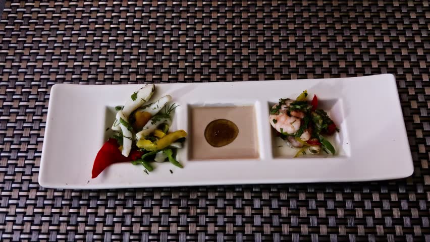 Elegant trio platter with marinated seafood, vegetables, and dipping sauce served on a modern table