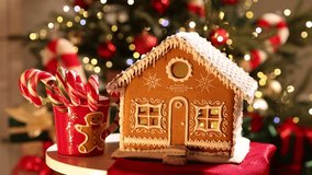Beautiful gingerbread house and cup with candy canes on table against flashing blurred lights and falling glitter, closeup. Christmas atmosphere - Powered by Shutterstock - Get 15% off with code: PIKWIZARD15