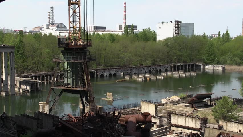Rusted Construction Crane And Dilapidated Concrete Structure At Abandoned Industrial Site In Chernobyl Exclusion Zone, Ukraine. high angle, zoom-in shot