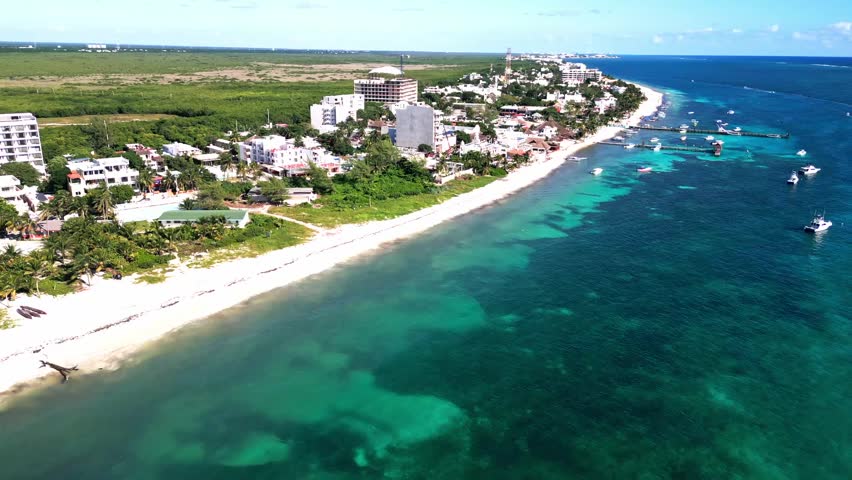 Cinematic aerial footage long the coastline of Puerto Morelos, Quintana Roo, Mexico, showing beaches, boats, turquoise water, and the town’s shoreline from above
