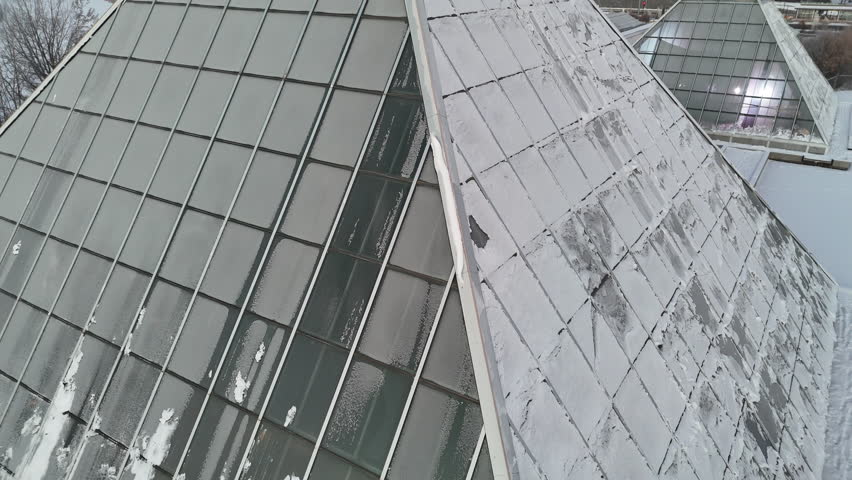 Direct overhead drone shot of a single frosty Muttart Conservatory pyramid surrounded by deep winter snow