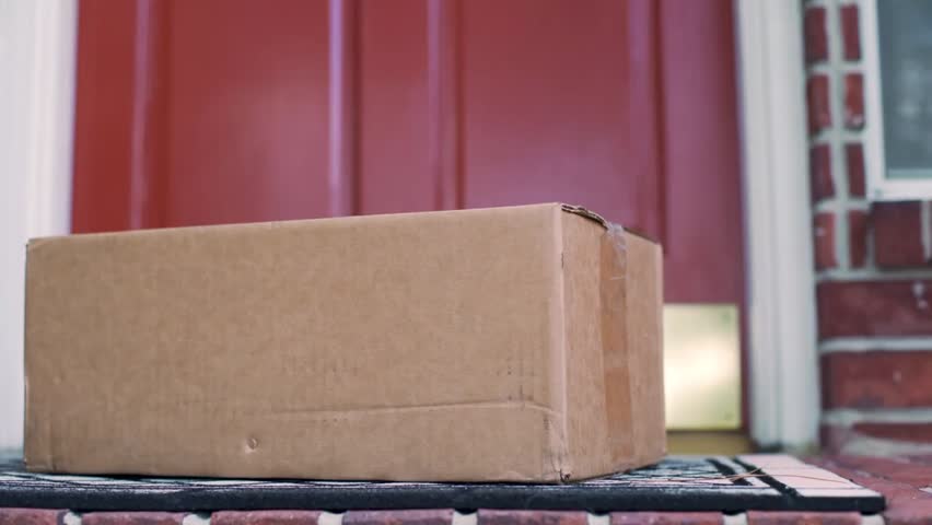 A closeup of a man picking up a delivery package from his doorstep, capturing modern home delivery, online shopping convenience, and contactless service.