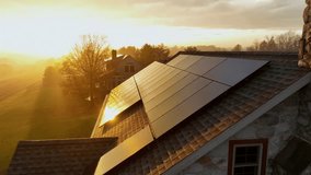 Flyover of an American home with rooftop solar panels glowing in golden sunrise, surrounded by late-autumn to early-winter fields and soft morning fog. Production of green energy theme. - Powered by Shutterstock - Get 15% off with code: PIKWIZARD15