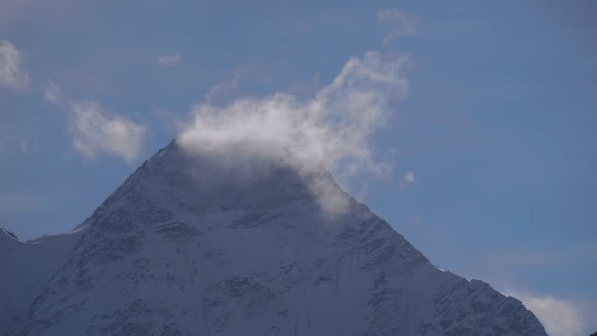 An awe inspiring view of the majestic Mount Elbrus, the highest peak in Russia and Europe, rising above the clouds in the North Caucasus region. The snow capped mountain stands out against a clear blu