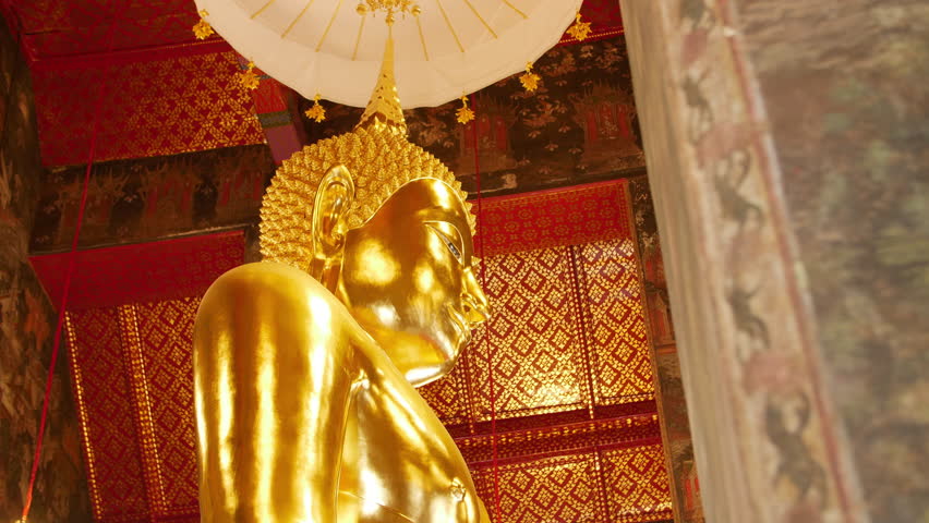 Golden standing Buddha statue inside a Thai temple, featuring detailed gold surfaces, traditional patterns, and cultural craftsmanship.
