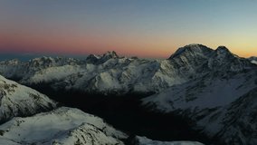 A panoramic view of the snow capped Greater Caucasus mountain range at sunset. The soft, warm light of the setting sun bathes the peaks in a beautiful alpenglow, creating a serene and breathtaking lan - Powered by Shutterstock - Get 15% off with code: PIKWIZARD15